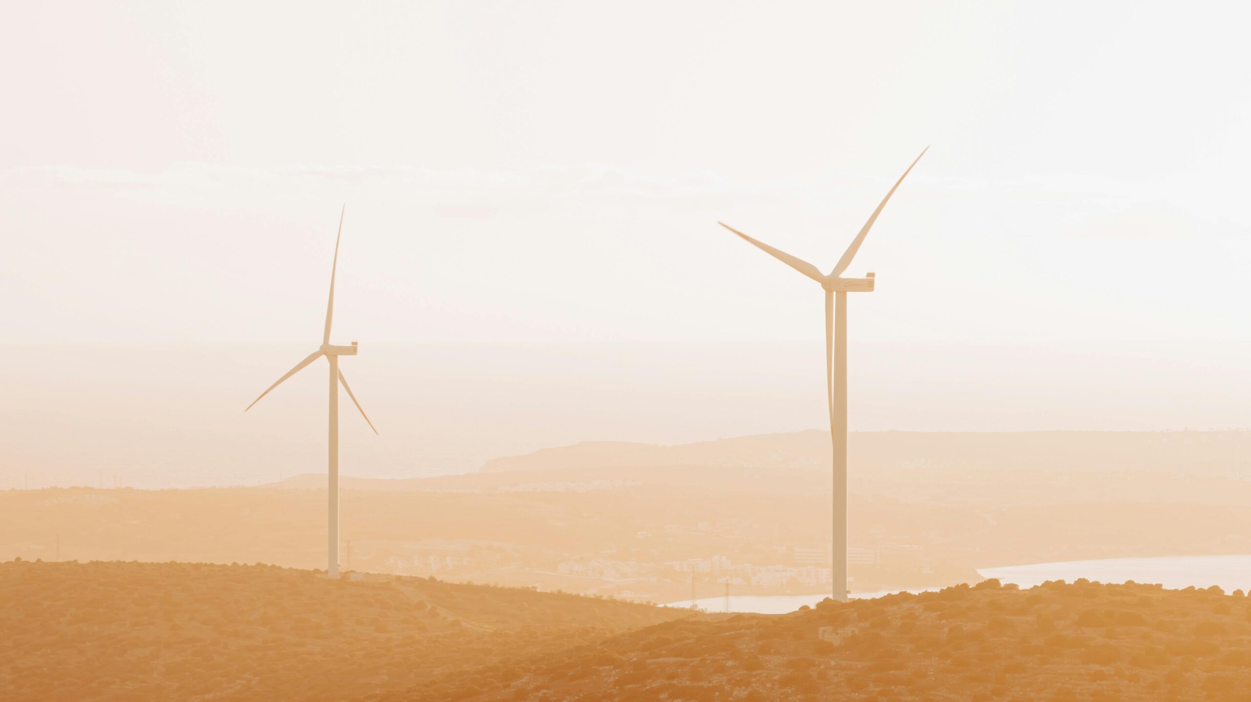 Aerial view of wind turbines on hills during sunset in Çeşme, Türkiye, showcasing renewable energy.