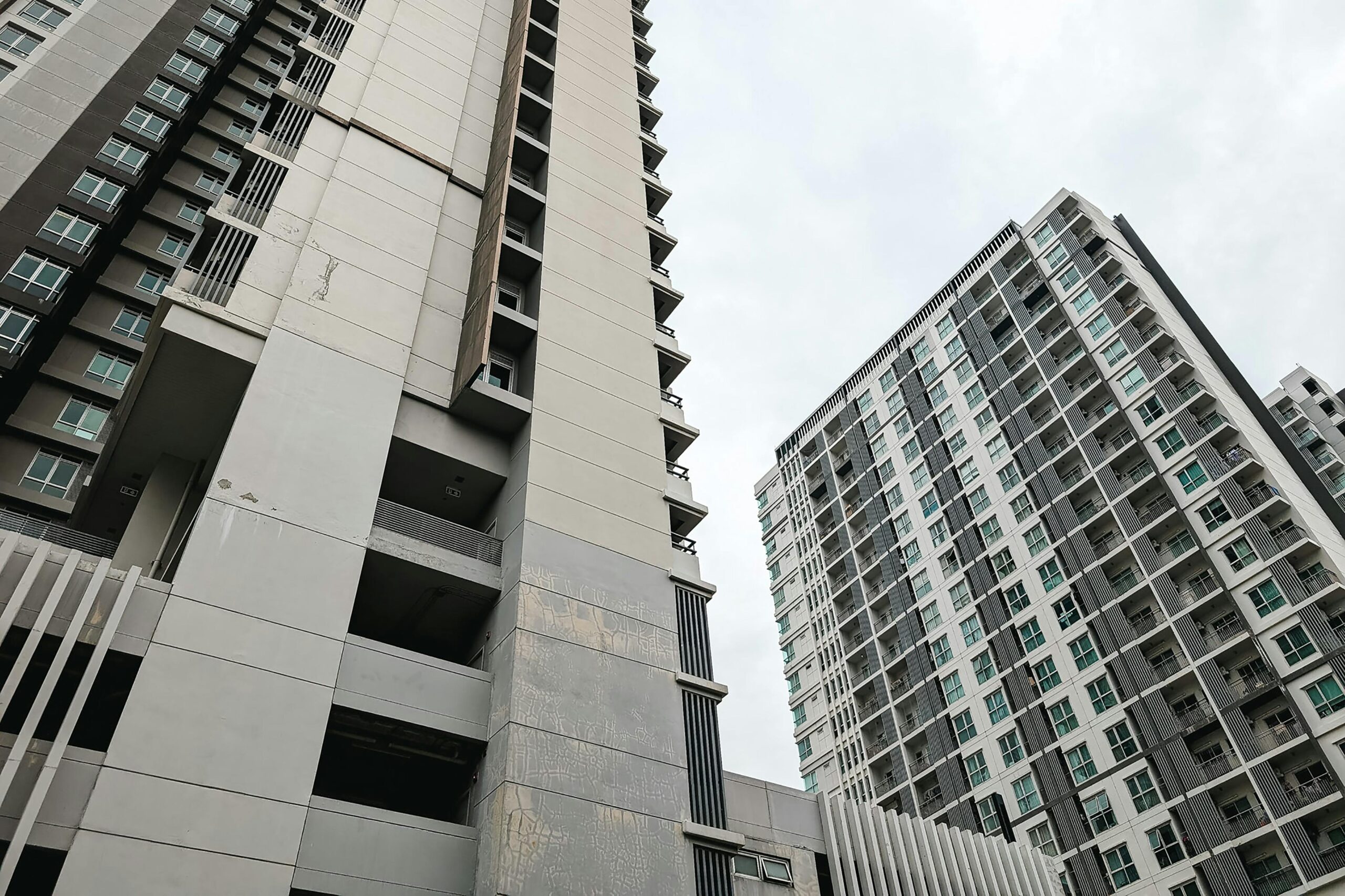 Modern urban high-rise buildings with balconies under a cloudy sky.